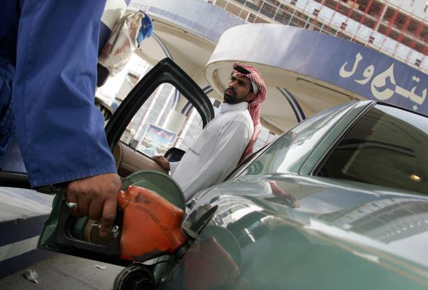 A worker at a gas station fills a Saudi